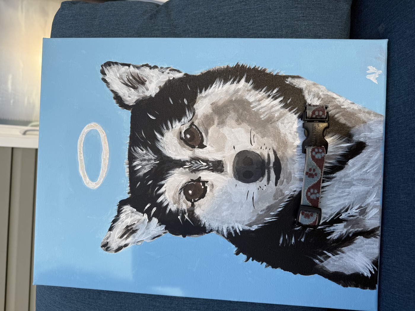 Acrylic portrait of a beloved dog with a halo, painted on a blue background