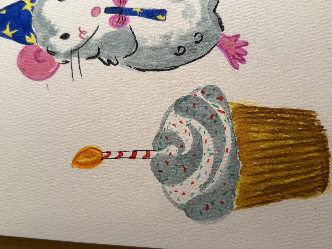 Watercolor painting of a mouse in a party hat next to a birthday cupcake